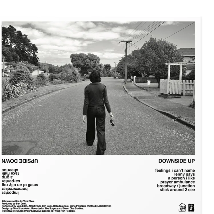 Back cover for Ideal Home Noise — a black and white photograph of a figure walking away down a suburban street, with the tracklist and credits printed upside down beneath it.