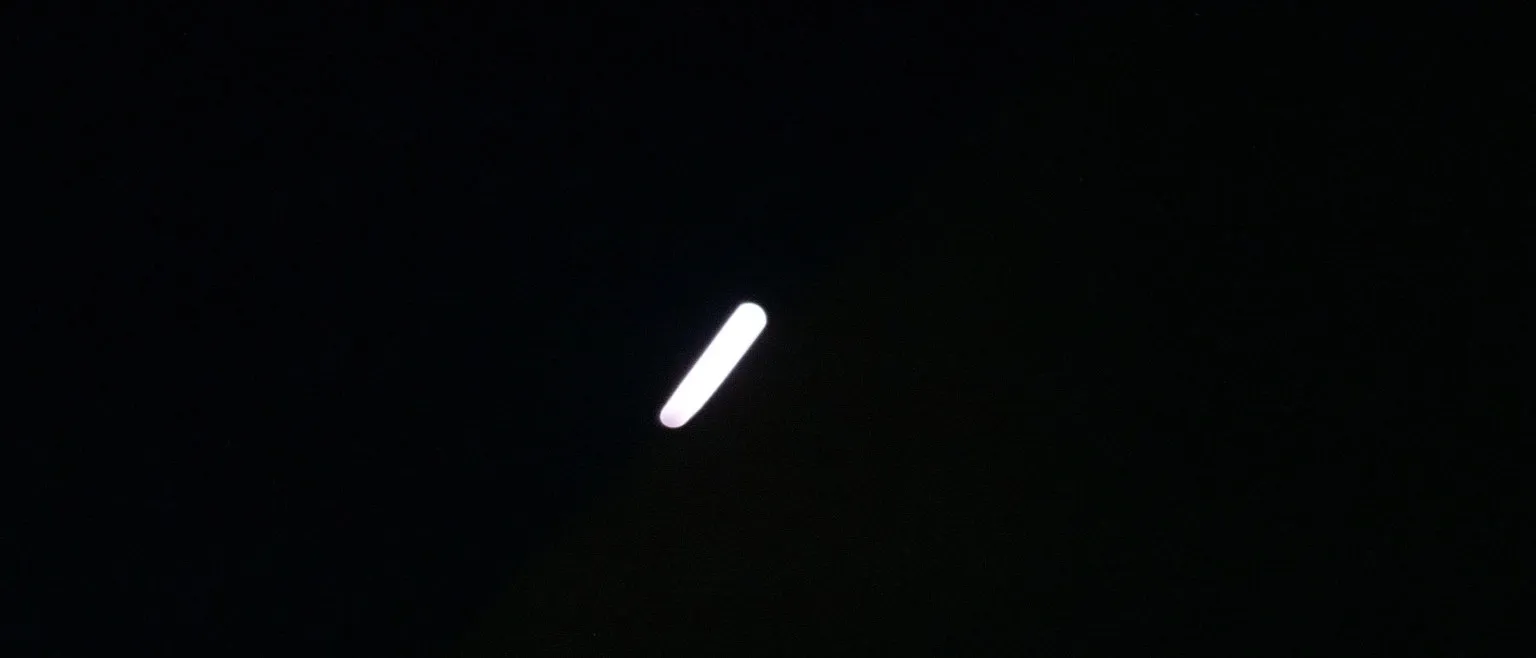A single streak of white light angled across total darkness, its edges softened to a blur.