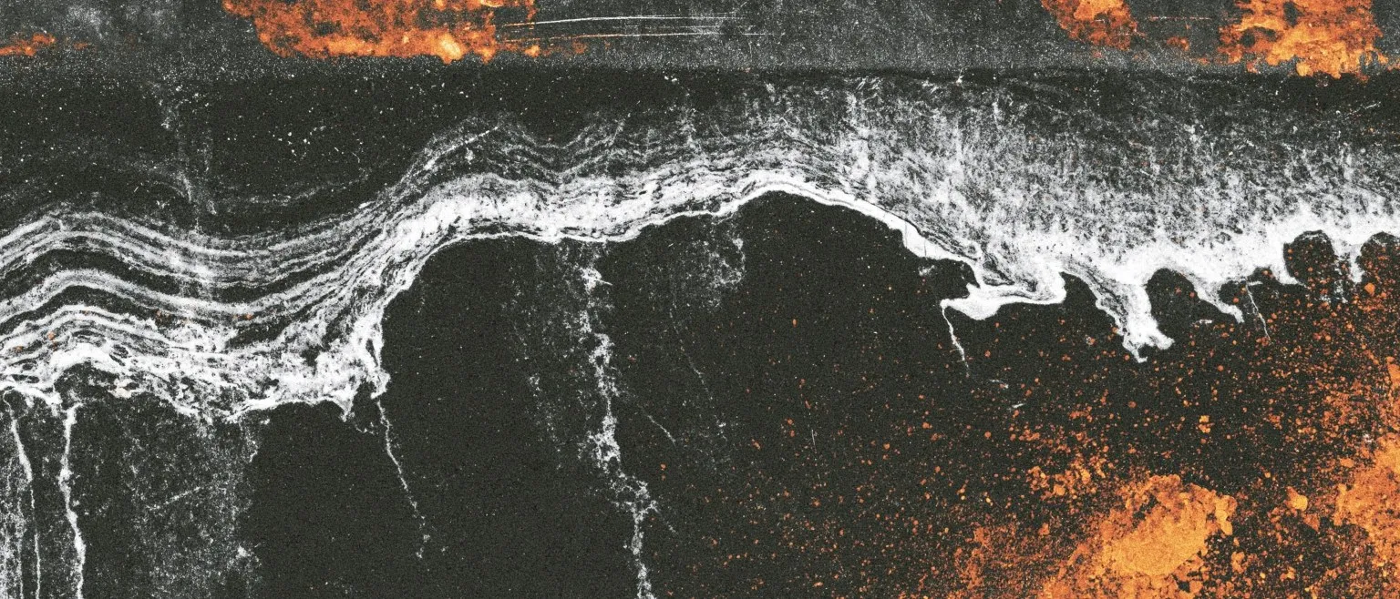 A white crested ridge over black, orange spatter along the base.